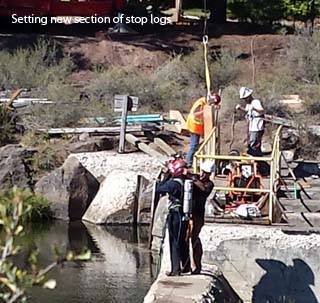 divers Setting new section of stop logs